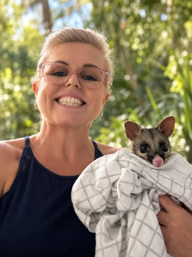 Megan holding a rescued brushtail possum wrapped in a towel