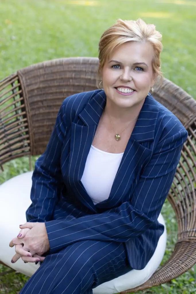 Megan Grant, founder of Plentifor, seated outdoors in a navy pinstripe suit